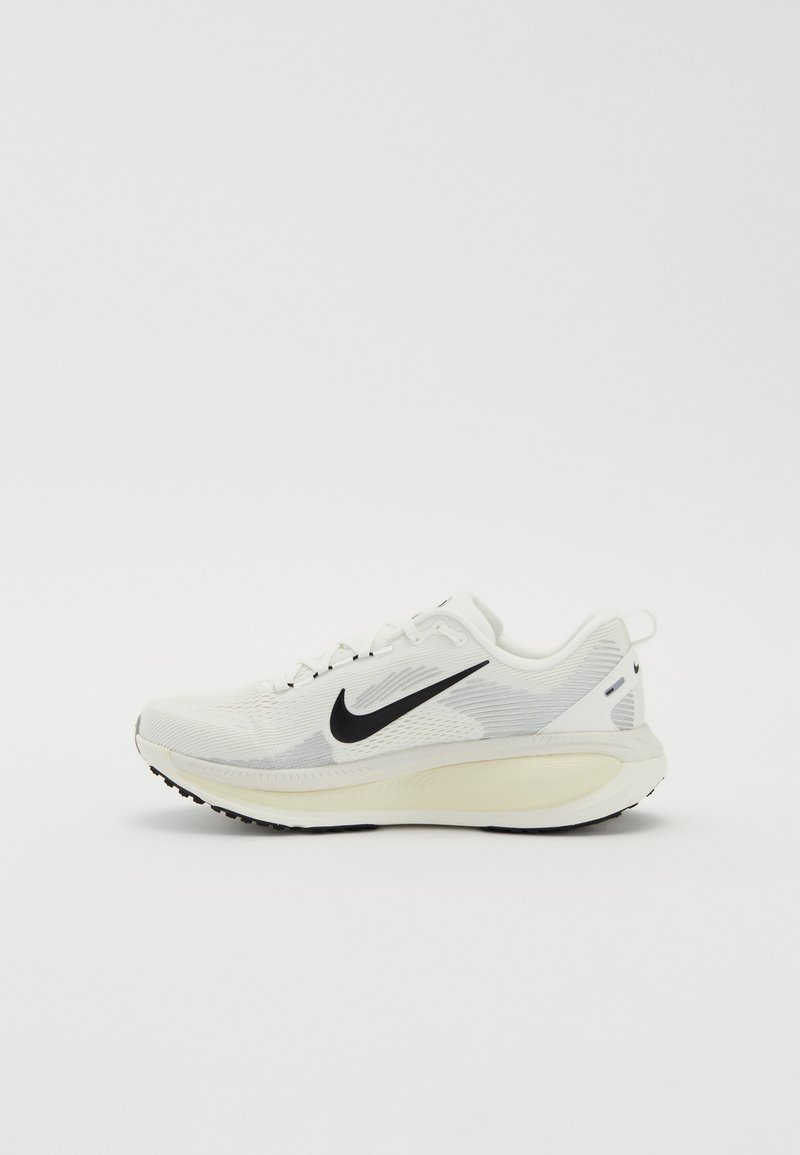 Baskets de sport blanches avec le swoosh Nike noir, semelle rembourrée et empeigne en mesh, vues de profil sur un fond clair uni.