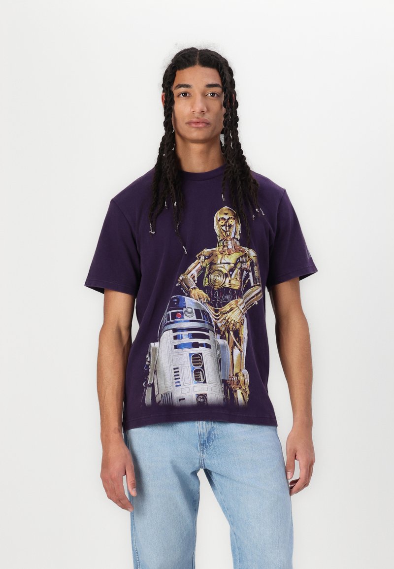 Lilla bomulds T-shirt med et grafisk tryk af C-3PO og R2-D2. Designet inkluderer detaljerede farver og teksturer af figurerne.