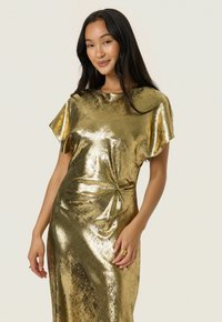 Rochie metalică aurie cu mâneci scurte, decolteu rotund și detaliu cu nod răsucit la talie. Textură de țesătură netedă și reflectorizantă.