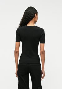 Svart strikket topp med korte ermer, rund hals og en figursydd design. Glatt tekstur med minimale sømmer og ingen synlig merking.