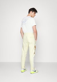 Nike Sportswear Calças de fato de treino - coconut milk/white/dark driftwood