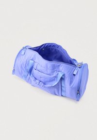 Κυλινδρική τσαντα duffel ανοιχτού πάνω μέρους σε ανοιχτό μωβ χρώμα, με διπλούς ιμάντες, πλαϊνές τσέπες και μικρό εσωτερικό διαμέρισμα με φερμουάρ.