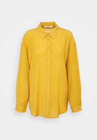 Camicia gialla con bottoni, tessuto testurizzato, maniche lunghe e colletto, con bottoni frontali e una silhouette morbida.