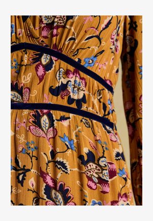 Blumenkleid aus senfgelbem Stoff mit blau, pink und lila Mustern, mit navyblauen Samt-Akzenten und einer strukturierten Oberfläche.