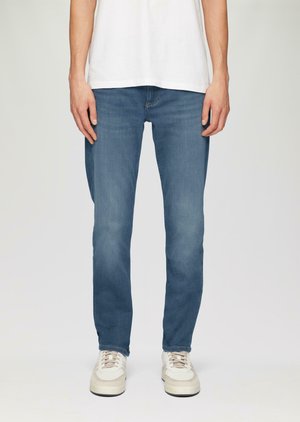 Lichtblauwe denim jeans met een rechte pijp, gedetailleerde stiksels en een zachte textuur, gecombineerd met sneakers in neutrale tinten.