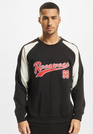 Sweat à capuche noir avec des manches raglan blanches, logo "Rocawear" en rouge et impression "99" sur le devant, finitions en côte aux poignets et à l'ourlet. Matière en mélange de coton.