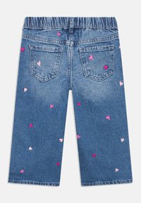 Džínsy z denimu s elastickým pásom, svetlomodrej farby, zdobené ružovými vyšívanými vzormi srdiečok rozmiestnenými po celej látke a na zadných vreckách.