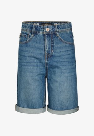 Zielona bawełniana koszulka polo z krótkim rękawem i naszywką na piersi, zestawiona z dżinsowymi szortami, białymi skarpetkami i białymi trampkami.