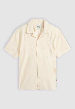 Κοντομάνικο πουκάμισο σε εκρού χρώμα με κουμπιά, με διακριτική κεντητική άνθη στο μπροστινό μέρος και γιακά τύπου κάμπ, τοποθετημένο επίπεδα σε γκρι φόντο.