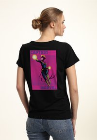 Camiseta negra de algodón con un gráfico vibrante impreso de un superhéroe en vuelo, con acentos morados y rosas, y el texto "CAPTAIN MARVEL."