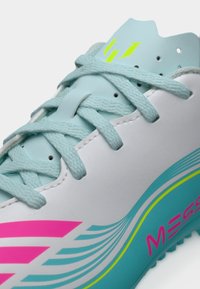 Λευκό και ανοιχτό μπλε ποδοσφαιρικό παπούτσι με ροζ και πράσινες λεπτομέρειες, κατασκευασμένο από λείο συνθετικό υλικό, με στρογγυλά κορδόνια και υφή στη σόλα.