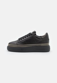 Schwarzes Leder-Sneaker mit abgerundeter Zehenpartie, flachen Schnürsenkeln und einer dicken schwarzen Sohle mit einem goldenen Akzentstreifen entlang der Mittelsohle.