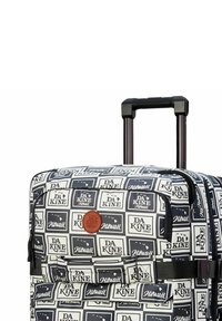 Rolling suitcase with a white background, navy graphic squares, and brown leather logo patch. Features extendable handle and zippered compartments.