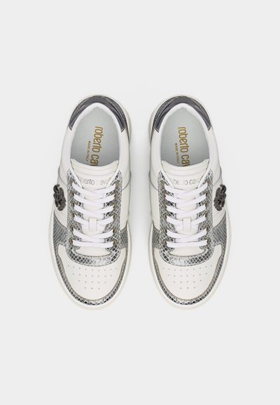 Λευκά και ασημί αθλητικά παπούτσια με σχέδιο δέρματος φιδιού, λευκά κορδόνια, διάτρητα μπροστινά μέρη και λογότυπο στο εσωτερικό των τακουνιών.