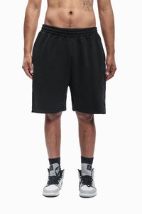 Sorte svette-shorts med elastisk midjebånd, glatt tekstur, kne-lengde, brukt med grå og hvite høy-top sneakers og svarte sokker.