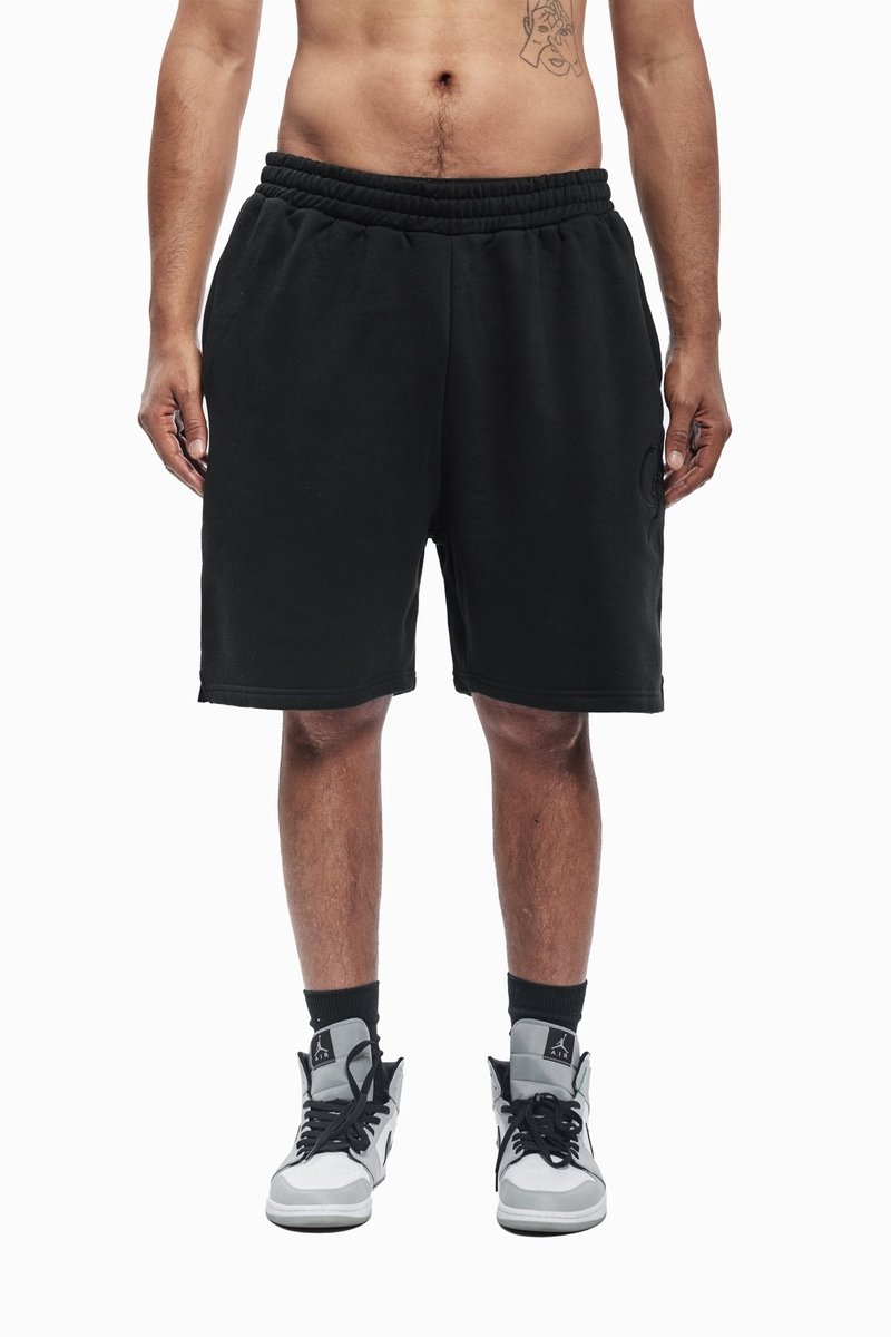 Sorte svette-shorts med elastisk midjebånd, glatt tekstur, kne-lengde, brukt med grå og hvite høy-top sneakers og svarte sokker.
