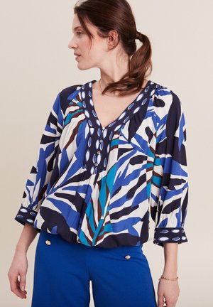 Blusa multicolore con scollo a V, caratterizzata da motivi astratti blu, bianchi e marroni. Maniche lunghe e tessuto testurizzato con dettagli di bottoni.