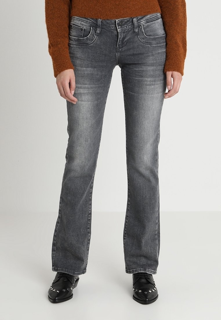 Donkergrijze denim jeans met een rechte pijp, lichte vervaging en vijf zakken. Gestyled met zwarte schoenen met zilveren accenten.