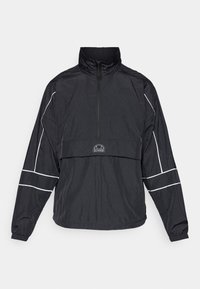 Czarna sportowa kurtka z długim rękawem i półzamkiem, z białymi przeszyciami na rękawach oraz logo Ellesse na klapce przedniej kieszeni.