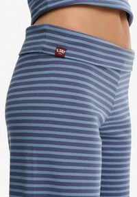 Gestreepte sporttop en broek in marineblauw en lichtblauwe tinten. Zachte stof met een aansluitende pasvorm. Bevat een klein rood label op de tailleband.