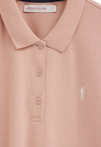 Lichtroze poloshirt met een kraag, drie knopen, een klein wit polo-spelerlogo op de borst en een maat S-label aan de binnenkant van de kraag.
