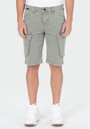 Man wearing light gray cargo shorts and white sneakers, standing against a plain background.