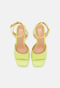 Pair of lime green open-toe sandals with ankle straps and quilted detailing, showing tan insoles branded "BULL BOXER."