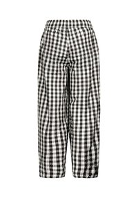 Pantalon ample à carreaux noir et blanc avec taille élastique et texture de tissu légèrement froissée, présenté sur fond blanc.