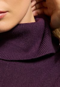 Maglione a collo alto viola con colletto a coste e morbida texture, aderente al collo, caratterizzato da sottili variazioni nello spessore del tessuto.