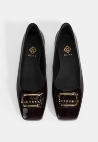 Ballerines en cuir verni bordeaux avec un bout carré, dotées d'une boucle dorée et d'une finition lisse et brillante.