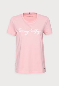 Růžové bavlněné tričko s krátkými rukávy, na přední straně s bílým nápisem "Tommy Hilfiger" a malým logem na lemu.