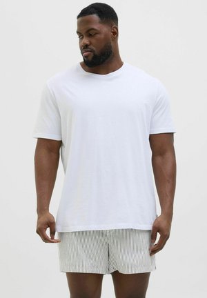 Vit t-shirt med rund hals i mjukt tyg, i kombination med ljusgrå och vita randiga shorts; båda har avslappnad passform med korta ärmar och inga synliga logotyper.