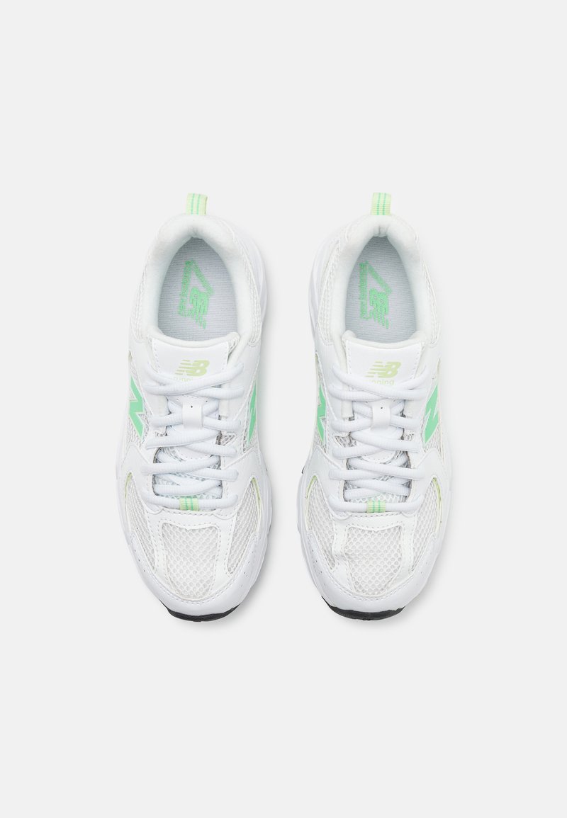 Zapatillas deportivas blancas que presentan materiales de malla y sintéticos, con detalles en verde, cierre con cordones y una suela texturizada.