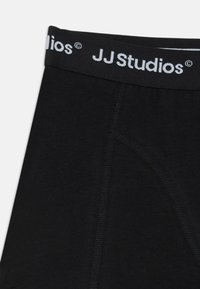 Svarte undertøy med en myk elastikk med "JJ Studios" trykket i hvitt. Glatt stoff med subtil søm og skreddersydd design.