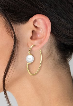 Orecchino a cerchio in oro con accento di perla bianca. Il cerchio ha un design ondulato e aperto, con una texture liscia.