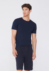 Námořnická modrá tričko s krátkými rukávy vyrobené z měkké bavlny, s kulatým výstřihem. V páru s odpovídajícími námořnickými šortkami s nastavitelnou šňůrkou.