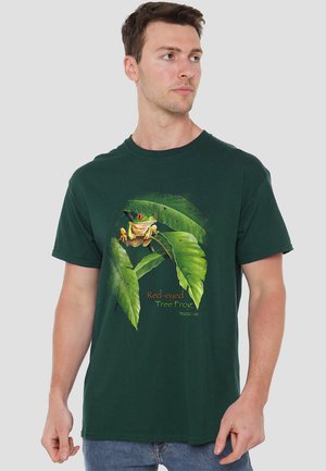 Dunkelgrünes Baumwoll-T-Shirt mit einem Design von einem rotäugigen Baumfrosch zwischen Blättern. Kurze Ärmel und runder Ausschnitt mit Grafikdruck.