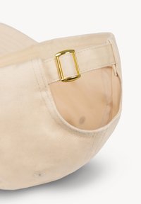 Beige stoffen petriem met gouden metalen verstelbare gesp, close-up afbeelding tegen een witte achtergrond.