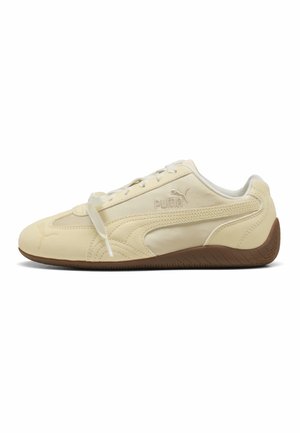 Sneaker Puma color crema con suola marrone, design con lacci e logo Puma sul lato, mostrato dal profilo esterno.