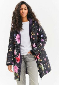 Černá prošívaná bunda s velkými růžovými a fialovými květinami, fialovou vnitřní výstelkou a žebrovanými manžetami. Nositelná přes bílou košili.