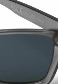 Occhiali da sole con montatura grigia, lenti scure e dettagli incisi tra cui "UK CA," "CE," "CAT.3," e "LOT 10/2023" sulla asta.