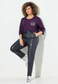 Lila långärmad skjorta med en bröstficka prydd med rhinestones, kombinerad med svarta läderbyxor och silvriga spetsiga stövlar.