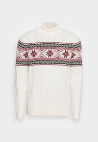 Bílý svetřík s vysokým límcem a pleteným vzorem, zdobený  červenými a tmavě zelenými geometrickými a hvězdnými motivy na hrudi a horních rukávech.