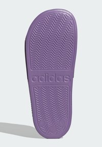 Fioletowa gumowa podeszwa obuwia z wzorem w rybie łuskę i logo "adidas". Posiada zaokrąglone krawędzie i wyraźną teksturę zapewniającą przyczepność.