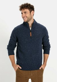 Granatowy sweter z dzianiny z wysokim kołnierzem i zamkiem błyskawicznym. Posiada ściągacze na mankietach i u dołu. Wykonany z fakturowanej przędzy z lekkimi przebłyskami.