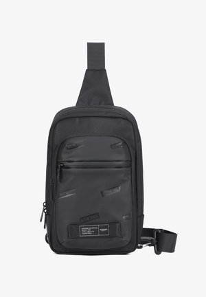 Borsa a tracolla nera realizzata in materiale resistente, con un pannello frontale liscio e loghi in rilievo, cinturino regolabile e scomparti con zip.