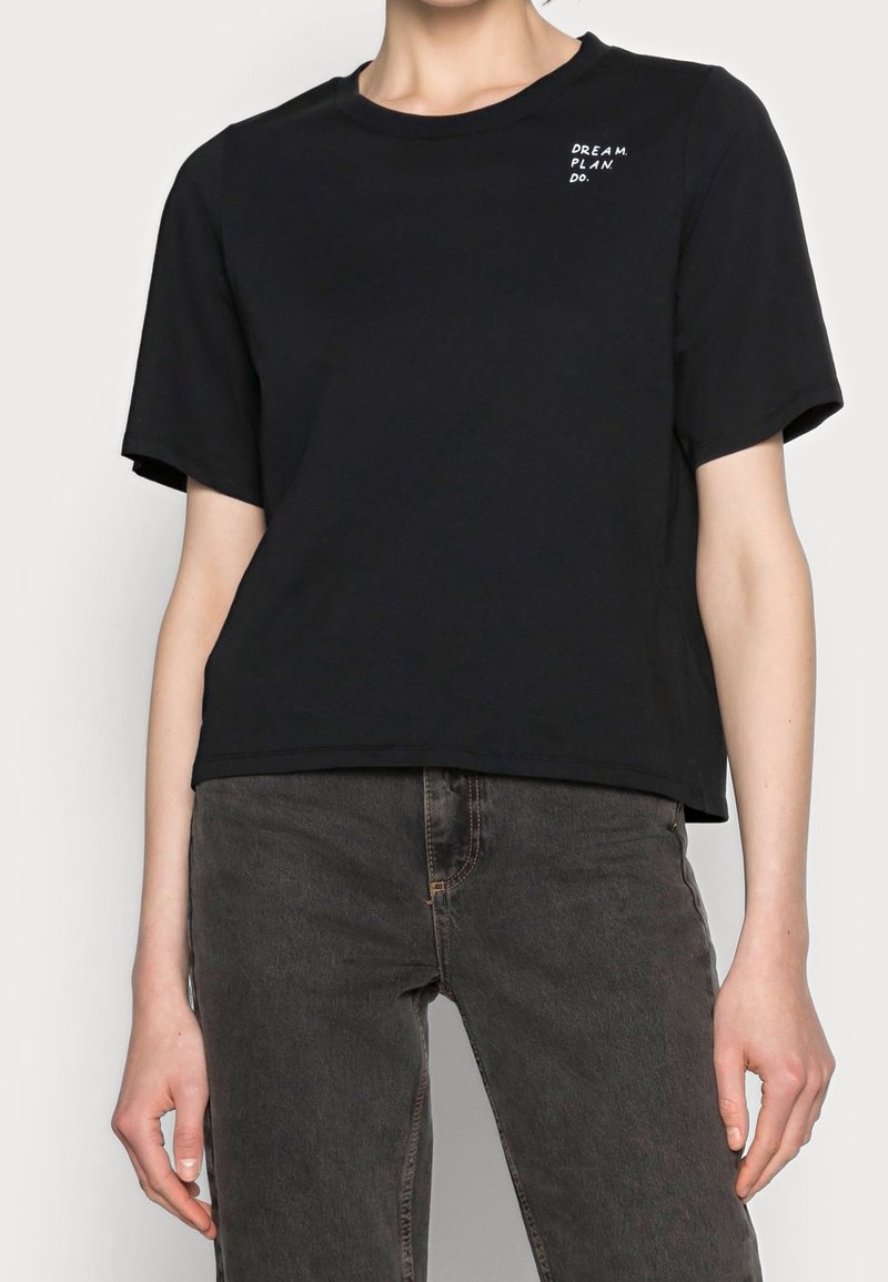 Camiseta de algodón negra con mangas cortas, que presenta un cuello redondo y el texto blanco "DREAM. PLAN. DO." en el área del pecho izquierdo.