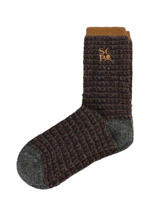 Calcetines tejidos con un patrón texturizado en tonos oscuros y un puño acanalado marrón. Incluye un detalle de logo en un color más claro en el tobillo.