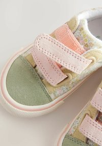Børnesneakers med en blomsterdesignet overdel i stof, udsmykket med grøn og lyserød ruskind. Lukning med to justerbare velcrostropper. Gummisål.
