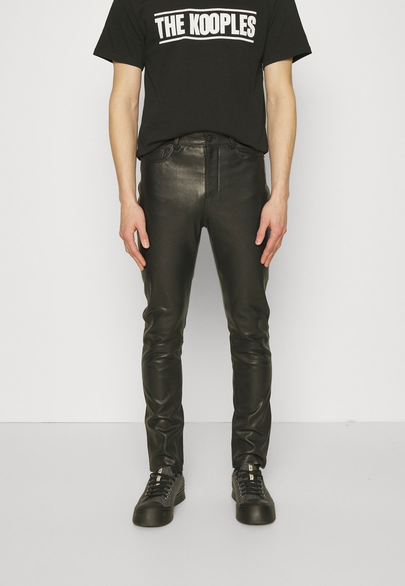 Svarta läderbyxor med slim fit, med en slät yta och klassisk femfickdesign. Matchas med en svart t-shirt med logotyp och sneakers.